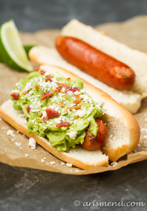 Spicy Bacon Guacamole Dogs: Spicy grilled hot dogs smothered with roasted jalapeno & garlic bacon guacamole + cotija cheese